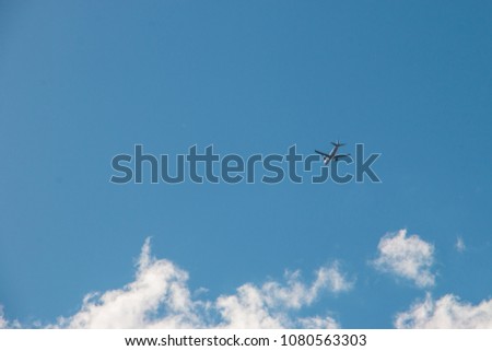 a picture of a passenger plane flying high in the sky on the background of a bright blue sky with clouds