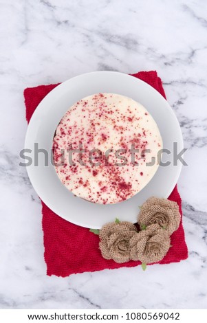 Vertical image of a red velvet cake on a red cloth, taken on a marble background  