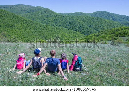 Family with two children resting on a meadow in a hike through mountains