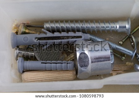 Wood screws and screws in a plastic workshop container. Fitter accessories in the toolbox. Light background.