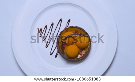 Top view of piece of balls of vanilla ice cream watered with chocolate on white dish isolated on a white background. Stock. All sprinkled with powdered sugar. Chocolate cheesecake with mint petal