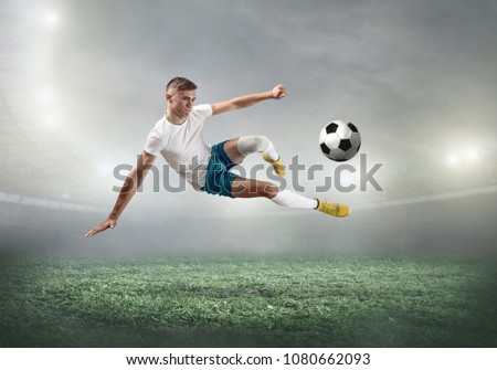 Soccer player on a football field in dynamic action at summer day under sky with clouds. Sporty man is shooting the ball outdoor.