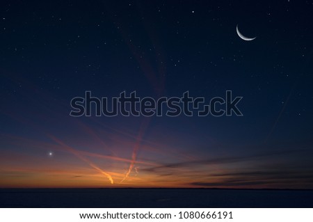 Night sky with stars, crescent Moon, planet Venus and airplane vapour trails.