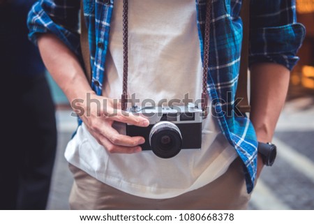 Man hanging film camera on neck at walking street and travel concepts.