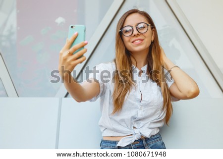 young attractive cute casual smiling girl is having fun and taking selfie on smartphone