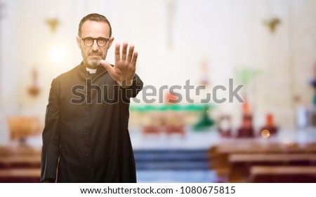 Priest religion man annoyed with bad attitude making stop sign with hand, saying no, expressing security, defense or restriction, maybe pushing at church