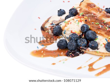 Vanilla Ice Cream decorated with Blueberries and topped with caramel Syrup isolated on white background