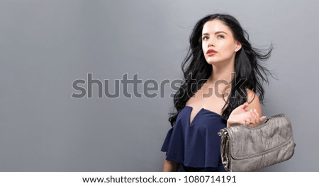 Fashionable woman with luxury handbag on a silver background