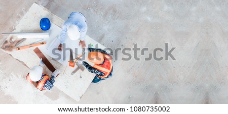 Team of young man and woman engineer and architects working, meeting, discussing,designing, planing, measuring layout of building blueprints in construction site floor at factory.top view & copy space Royalty-Free Stock Photo #1080735002