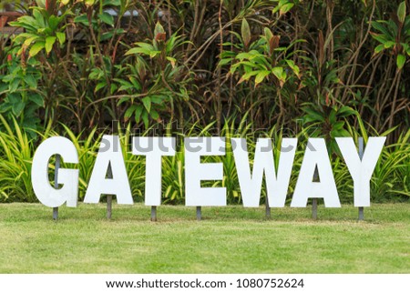 White metal text sign "Gateway" on lawn grass and green background decorated in garden