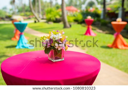 colorful beautiful orchid bouquet decor in glass vase setup on wooden dinner table in india wedding venue reception. Royalty-Free Stock Photo #1080810323