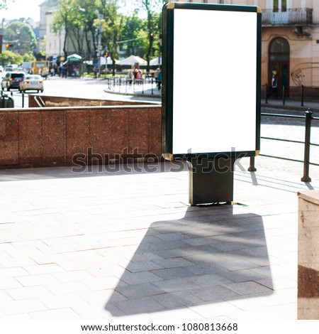 Blank vertical street billboard stand with city background.