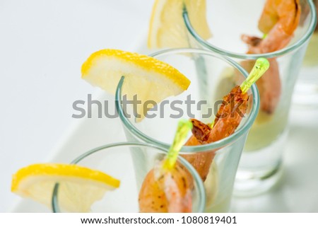 individual Cocktail Shrimp shot glasses with delicious homemade tartar spicy sauce decorated with parsley leaf for Christmas dinner or cocktail party, bokeh background