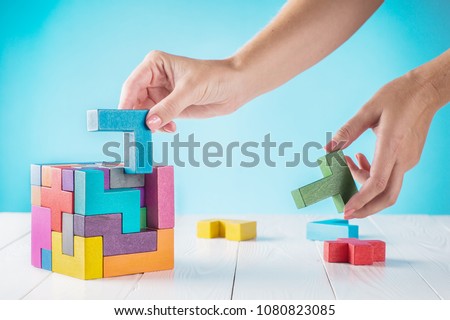 Concept of decision making process, logical thinking. Logical tasks. Conundrum, find the missing piece of the proposed. Hand holding wooden puzzle element. Hand sets the last element of the puzzle.  Royalty-Free Stock Photo #1080823085