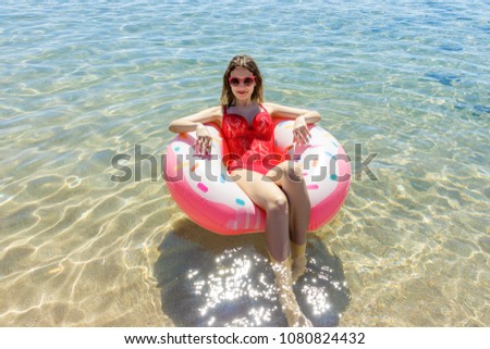 Beautiful young woman with inflatable ring relaxing in blue sea.