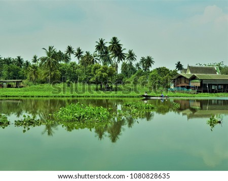 View of long tail boat and wooden house on the river.