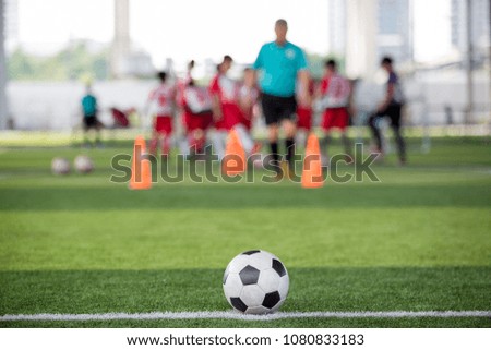 Ball on artificial turf with blurry soccer academy training background.