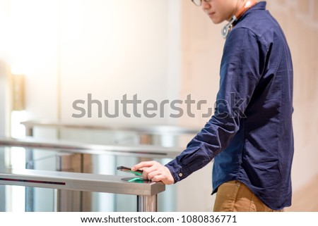 Young Asian business man using smartphone to open automatic gate machine in office building