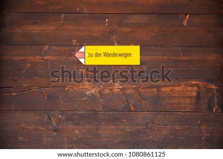 Hiking trail sign (zu den Wanderwegen) in the Swiss Alps. Wooden background texture on a old swiss house.