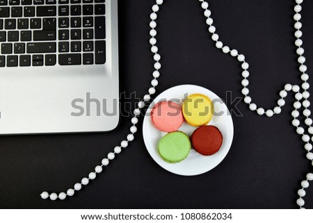 Sweet Dessert Macaron or macaroon, notebook. colorful almond cookies, cakes on blak background. Flat lay. Copy space. Woman Workplace. freelance
