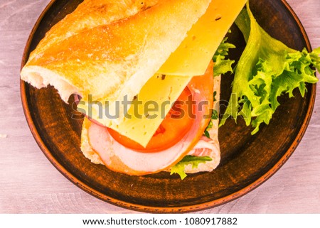 Delicious homemade sandwich with ham, cheese, tomatoes and lettuce on plate - top view