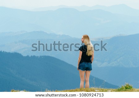 Young girl relaxing and enjoying scenic view on top of mountain.  Bliss, happiness. Beautiful summer nature landscape. Lonely young blonde teen traveler dreaming outdoor on vacation.  Romantic mood
