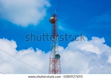 telecommunication tower in the middle of the picture with cloudy blue sky.