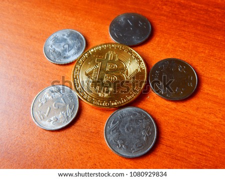 Bitcoin the crypto currency on table with Indian coins surrounding it, top view with little tilting of angle