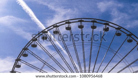 Ferris wheel before blue and cloudy sky