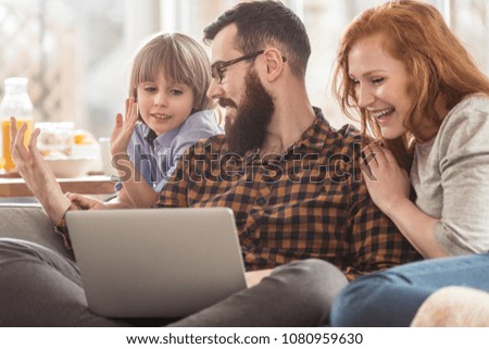 Happy son, mother and father watching a movie on a laptop together