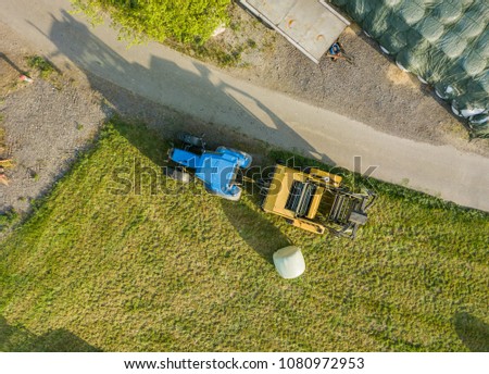 Aerial view of farm area with tractor standing in evening light 