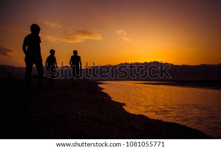Children playing and watching the sunset of the beautiful city of Dahab in Egypt