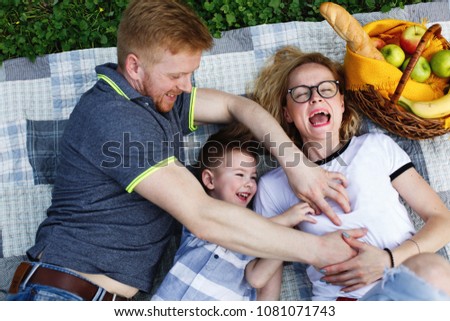 Laughing young family lies on the plaid in the park