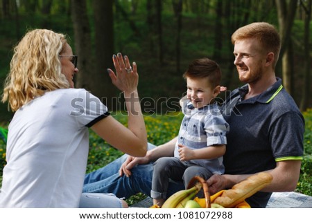 Young blonde mother plays with her son during a picnic in the park