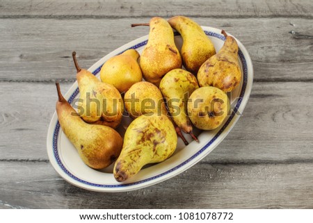 Table top view - oval plate with ripe pears placed on gray wood desk