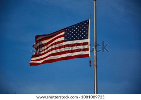 USA Flag flying at dusk with the wind having the field of stars in the upper right hand corner. 