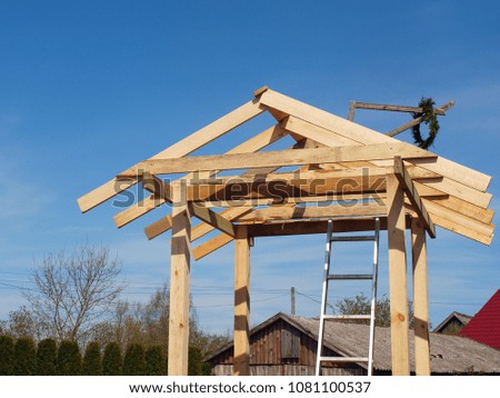 Wooden small house construction with roof rafters on sky background     