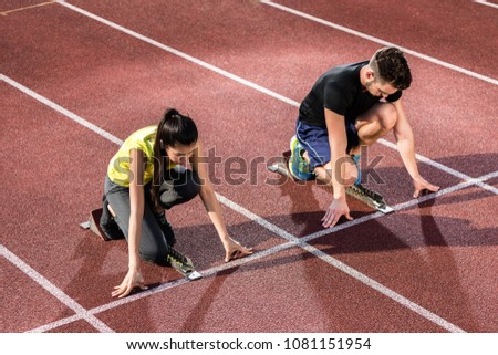 Male and female athlete in starting position at starting block of cinder track Royalty-Free Stock Photo #1081151954