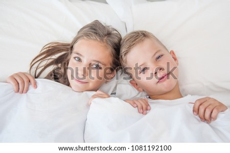 boy and girl lie under a blanket touching their hair
