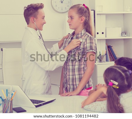 
Medic boy with stethoscope with patient girl in the doctor's office