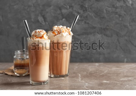 Glasses with delicious caramel frappe on table Royalty-Free Stock Photo #1081207406