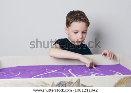 Sand animation. The boy draws his fingers on the interactive sand table.