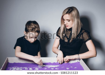 Sand animation. A young beautiful woman and a boy draw with their fingers on an interactive sand table. Training master class.