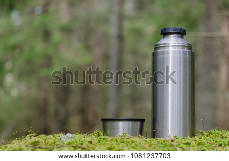 Leisure equipment - thermos and cup - in a green forest