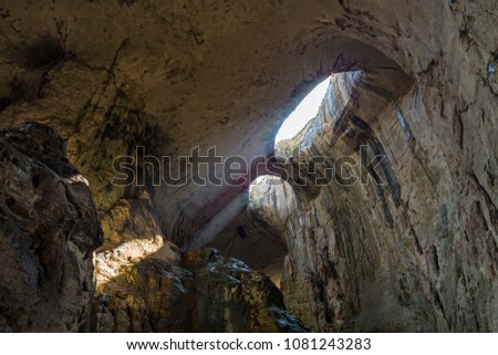 Prohodna cave also known as God's eyes near Karlukovo village, Bulgaria. Sun beams coming from the Gods eyes and lighting the cave.