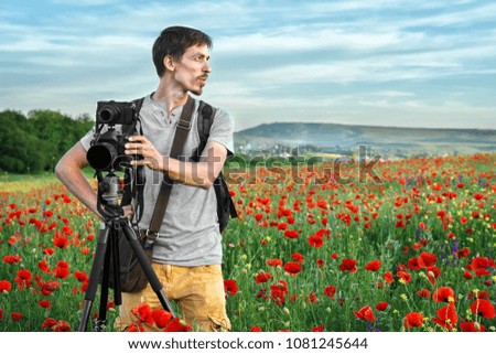Photographer man on the field of red poppies