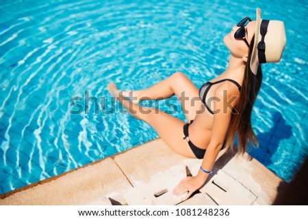 Beautiful young beauty woman sitting by swimming pool