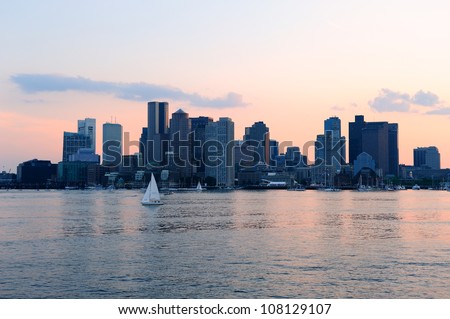 Boston downtown sunset skyline over river with skyscrapers and boat.