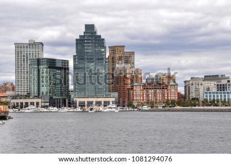 Tall, high-rise buildings line the shoreline of Harbor East on the Patapsco River at the mouth of the Inner Harbor in Baltimore, Maryland.