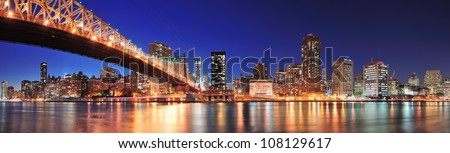 Queensboro Bridge over New York City East River at sunset with river reflections and midtown Manhattan skyline illuminated.